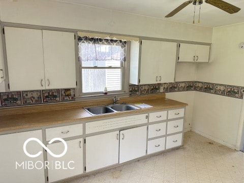 kitchen with sink, ceiling fan, light tile patterned flooring, and white cabinets