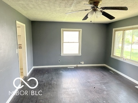 empty room with ceiling fan, plenty of natural light, and a textured ceiling