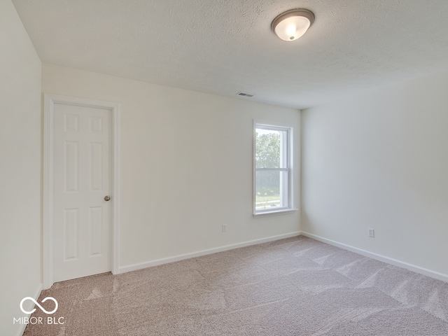 unfurnished room with light colored carpet and a textured ceiling