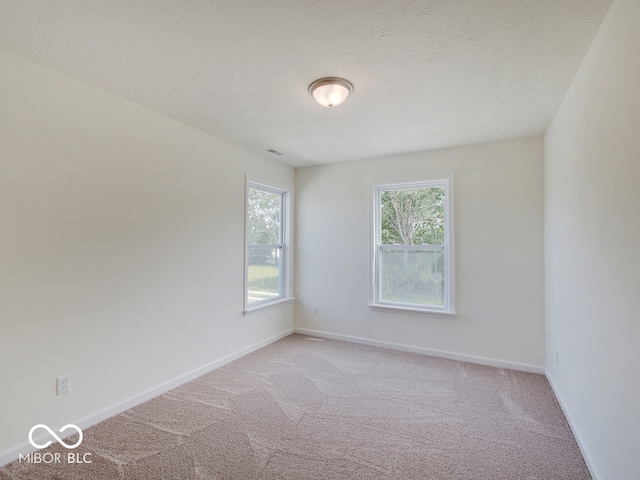 carpeted empty room featuring a textured ceiling