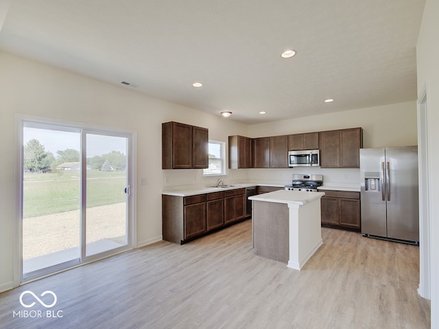 kitchen featuring a center island, sink, light hardwood / wood-style floors, dark brown cabinetry, and stainless steel appliances