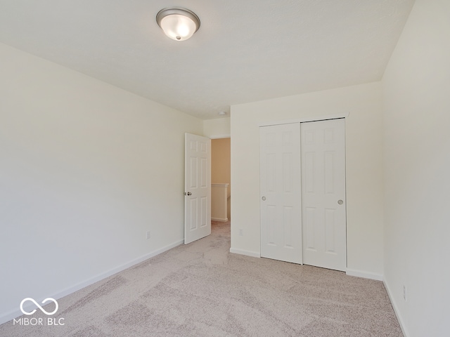 unfurnished bedroom with light carpet and a closet