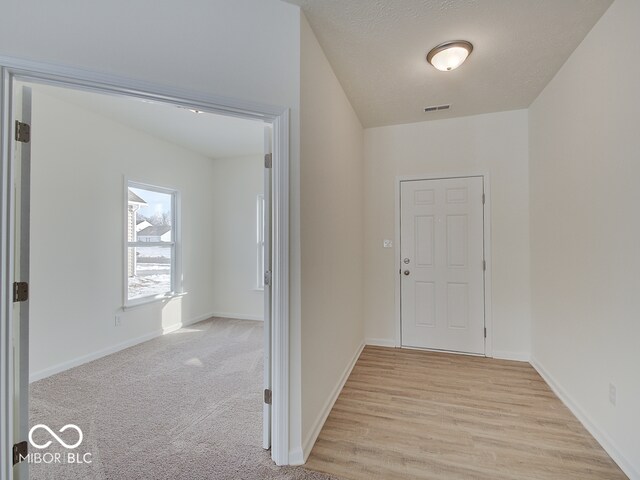 hallway featuring baseboards, visible vents, and a textured ceiling