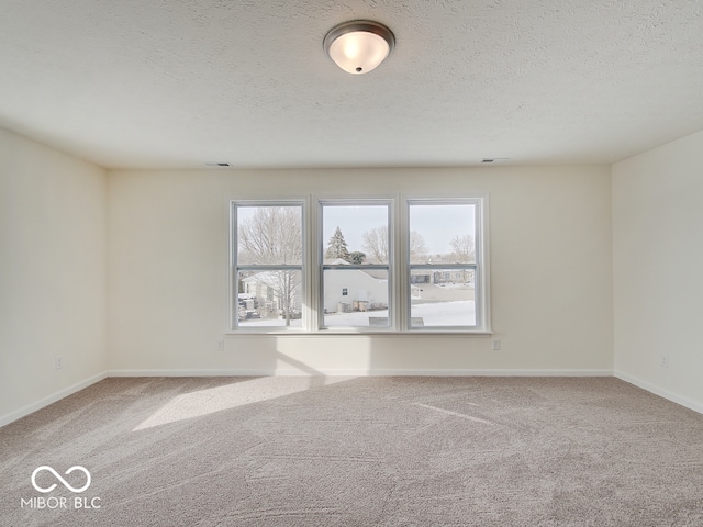 unfurnished room featuring baseboards, a textured ceiling, and light colored carpet