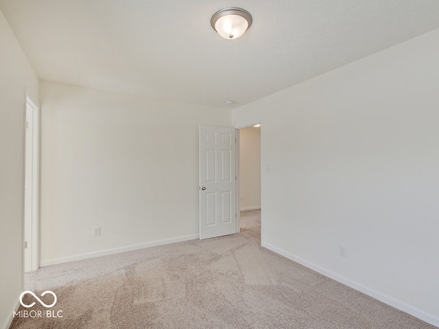 empty room featuring light carpet and baseboards