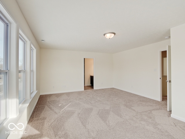 spare room with light carpet and baseboards