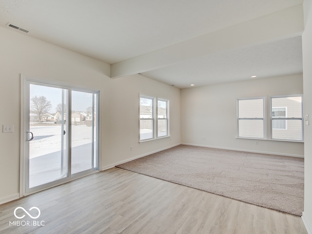 unfurnished room with light wood-type flooring, visible vents, and baseboards