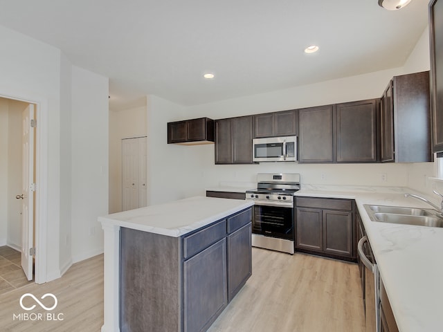 kitchen featuring light wood finished floors, appliances with stainless steel finishes, light countertops, and a sink