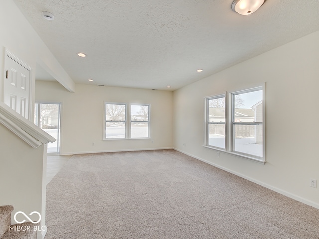 unfurnished living room featuring a textured ceiling, a wealth of natural light, and light colored carpet