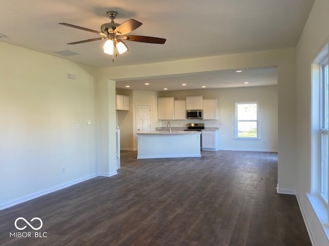 unfurnished living room featuring ceiling fan, dark hardwood / wood-style flooring, and sink