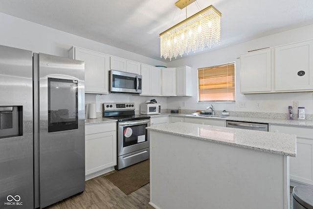 kitchen with a kitchen island, light hardwood / wood-style flooring, appliances with stainless steel finishes, a chandelier, and white cabinets