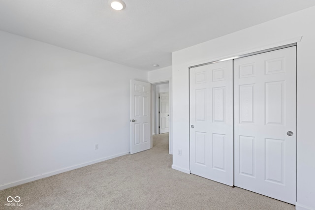 unfurnished bedroom featuring a closet and light carpet