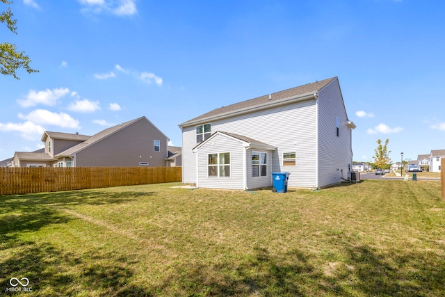 back of property with a yard and central AC