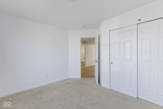 unfurnished bedroom with a closet and light colored carpet