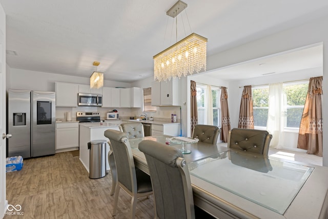 dining space with sink, a notable chandelier, and light hardwood / wood-style flooring