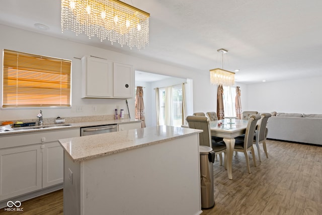 kitchen featuring a center island, a notable chandelier, white cabinetry, sink, and pendant lighting