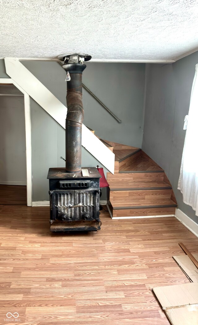 stairs with hardwood / wood-style flooring, a wood stove, and a textured ceiling