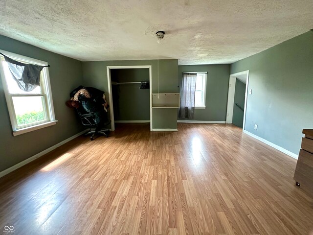 unfurnished bedroom featuring a textured ceiling, light hardwood / wood-style floors, and a closet