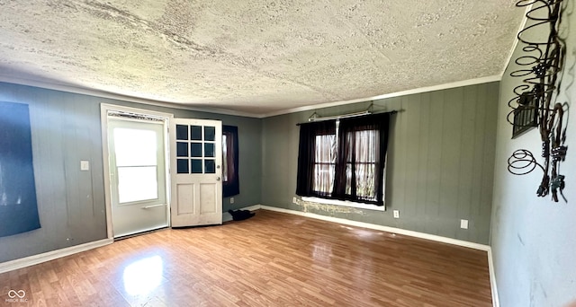 interior space featuring ornamental molding, wood-type flooring, a healthy amount of sunlight, and wooden walls