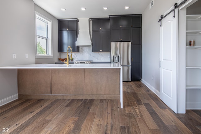 kitchen with a barn door, visible vents, light countertops, stainless steel refrigerator with ice dispenser, and dark wood finished floors