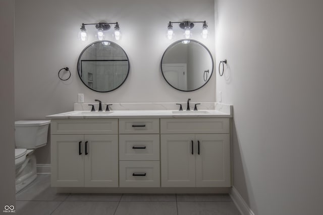 bathroom featuring baseboards, a sink, toilet, and double vanity