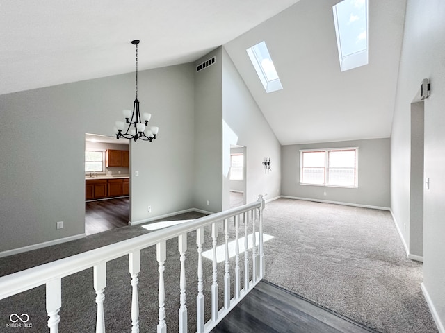 hallway with high vaulted ceiling, a notable chandelier, dark hardwood / wood-style flooring, and a skylight