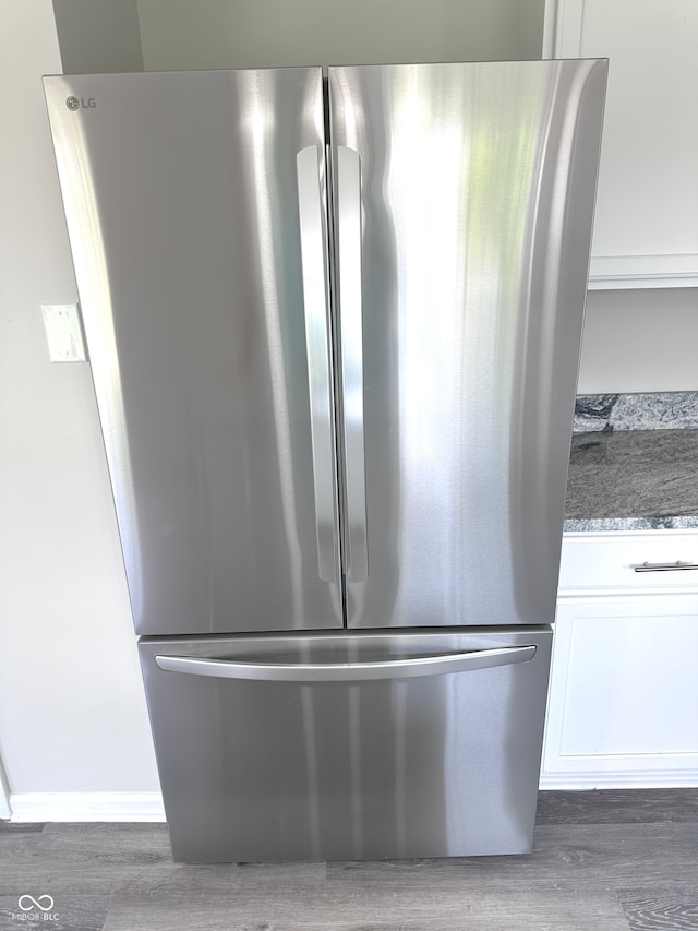 room details featuring hardwood / wood-style floors, stainless steel fridge, and dark stone countertops