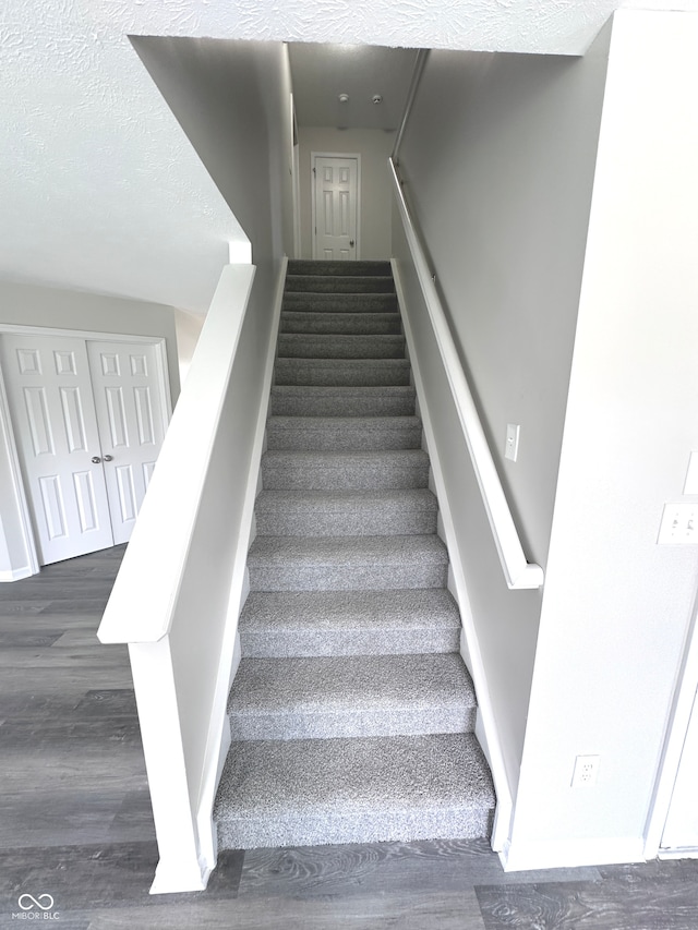 stairway with a textured ceiling and hardwood / wood-style floors