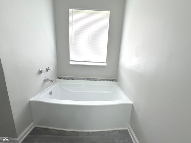 bathroom with a wealth of natural light, a bathing tub, and hardwood / wood-style floors