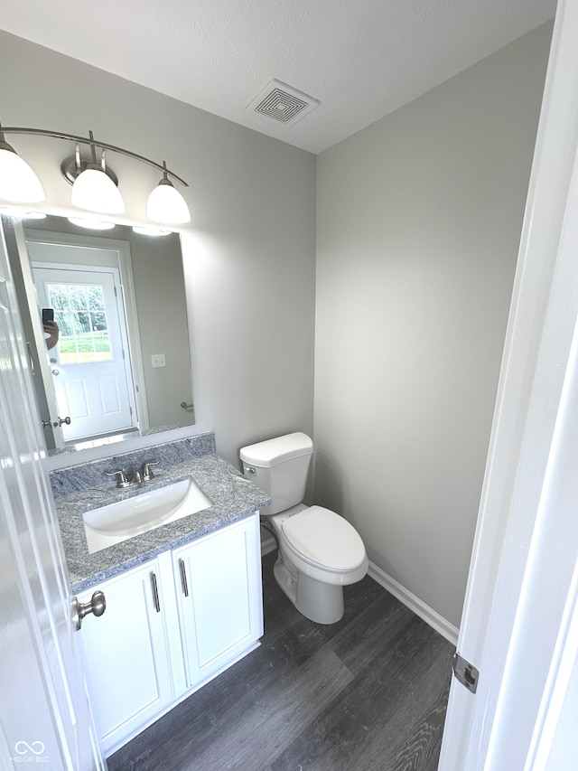 bathroom with wood-type flooring, toilet, a textured ceiling, and vanity