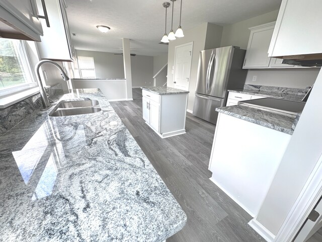 kitchen with custom range hood, a kitchen island, a healthy amount of sunlight, and dark hardwood / wood-style flooring