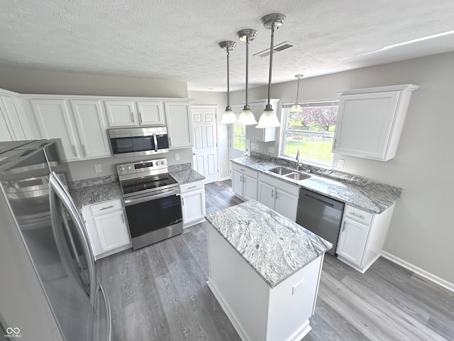 kitchen featuring hardwood / wood-style floors, appliances with stainless steel finishes, sink, and white cabinets