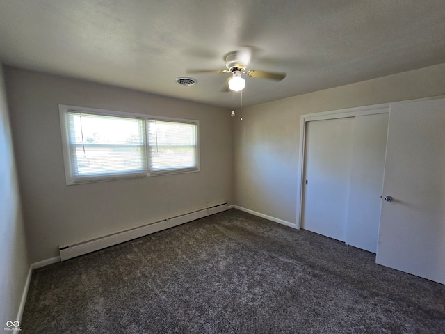 unfurnished bedroom featuring ceiling fan, a closet, baseboard heating, and dark colored carpet