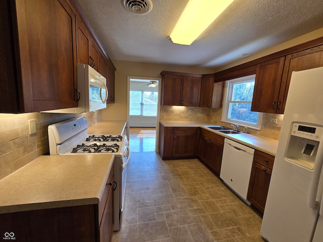 kitchen featuring decorative backsplash, a healthy amount of sunlight, and white appliances