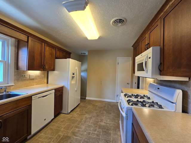 kitchen with backsplash, tile patterned floors, sink, a textured ceiling, and white appliances