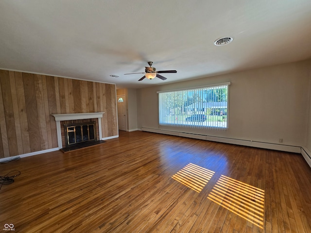 unfurnished living room with ceiling fan, wood-type flooring, a baseboard radiator, and a brick fireplace