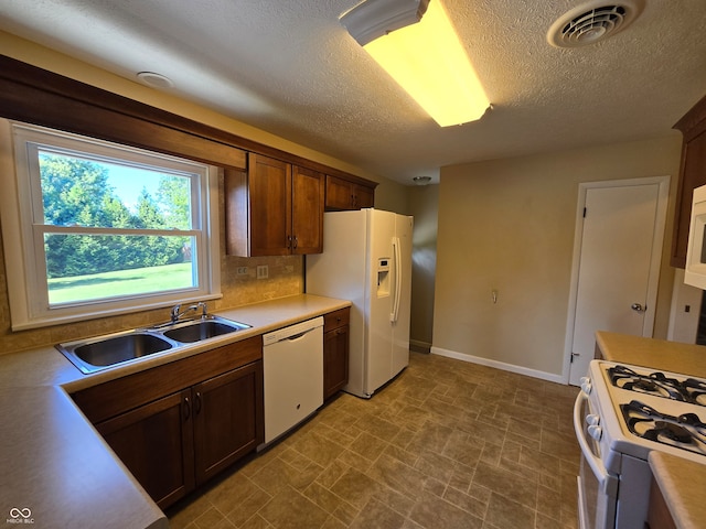 kitchen with sink, tile patterned floors, white appliances, tasteful backsplash, and a textured ceiling