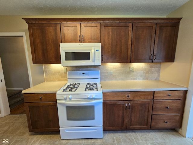 kitchen with light hardwood / wood-style floors, decorative backsplash, white appliances, and a textured ceiling