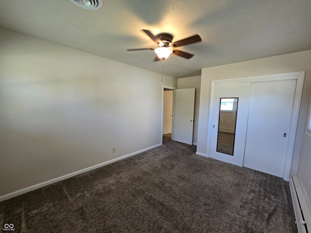 unfurnished bedroom featuring ceiling fan, a closet, dark colored carpet, and baseboard heating