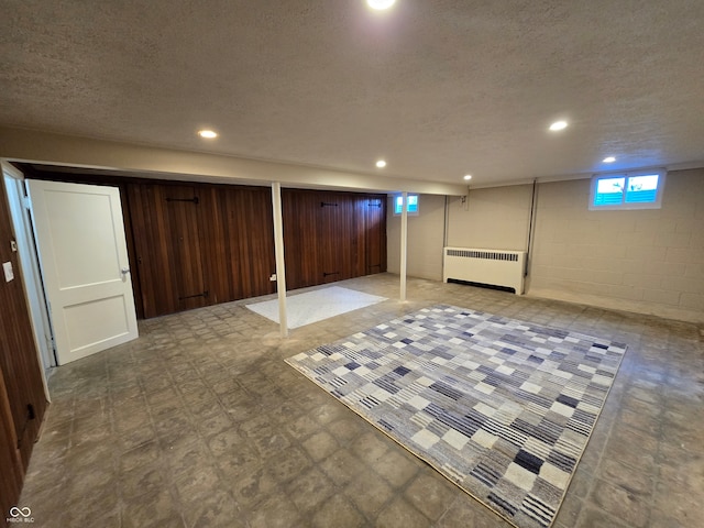 basement with a textured ceiling, tile patterned flooring, and radiator