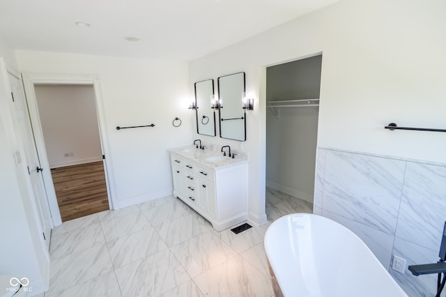 bathroom with tile walls, vanity, a bath, and tile patterned floors