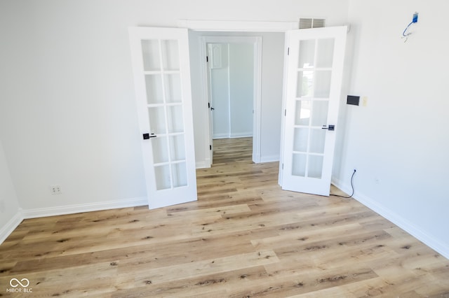 empty room with light hardwood / wood-style flooring and french doors