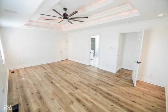 interior space with a tray ceiling, ceiling fan, light hardwood / wood-style floors, and crown molding