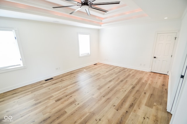 spare room featuring light hardwood / wood-style floors, a raised ceiling, crown molding, and ceiling fan