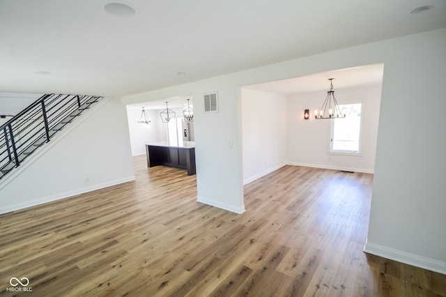 unfurnished living room featuring hardwood / wood-style floors and an inviting chandelier