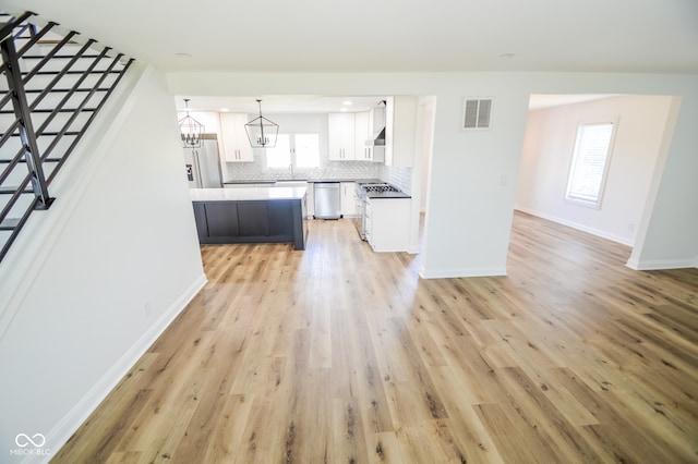 unfurnished living room featuring an inviting chandelier and light hardwood / wood-style floors