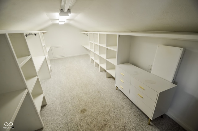 walk in closet featuring light carpet and lofted ceiling