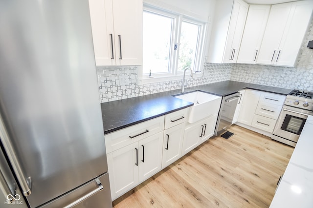 kitchen featuring sink, appliances with stainless steel finishes, light hardwood / wood-style floors, tasteful backsplash, and white cabinets