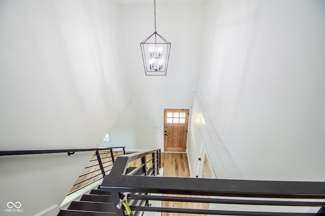 stairway with a high ceiling, a notable chandelier, and wood-type flooring