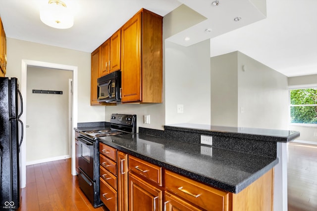 kitchen with hardwood / wood-style flooring, kitchen peninsula, black appliances, and wine cooler